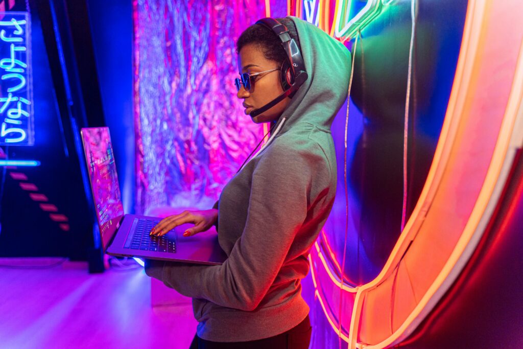 pexels-photo-5475786-5475786 A tech-savvy individual using a laptop in a neon-lit room, symbolizing cybersecurity.