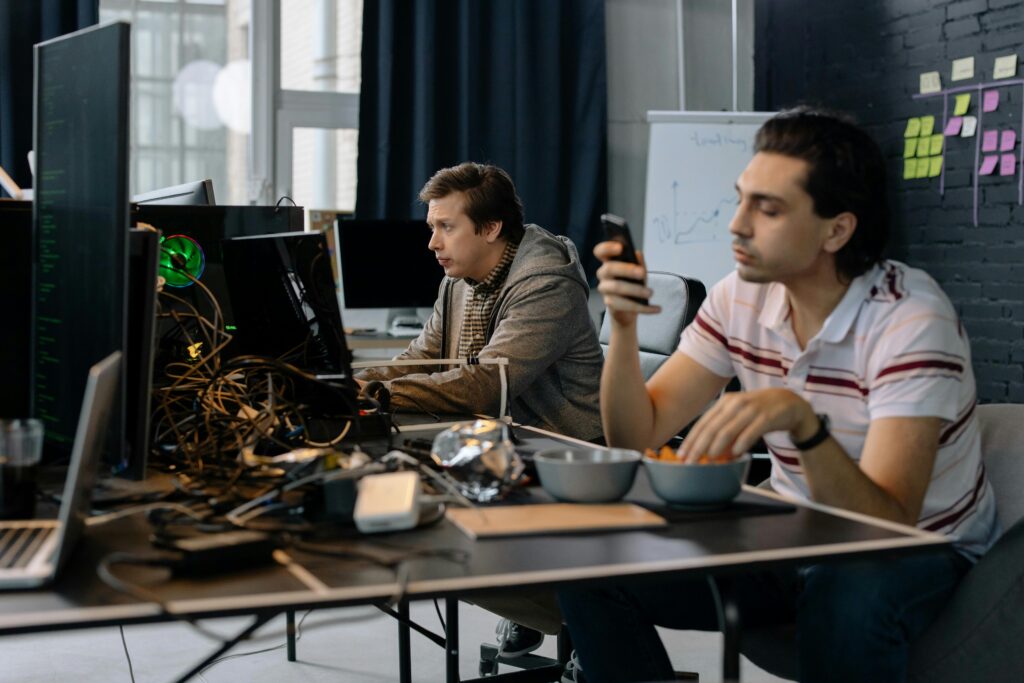 Two men working in a modern office setup, focused on technology and collaboration.