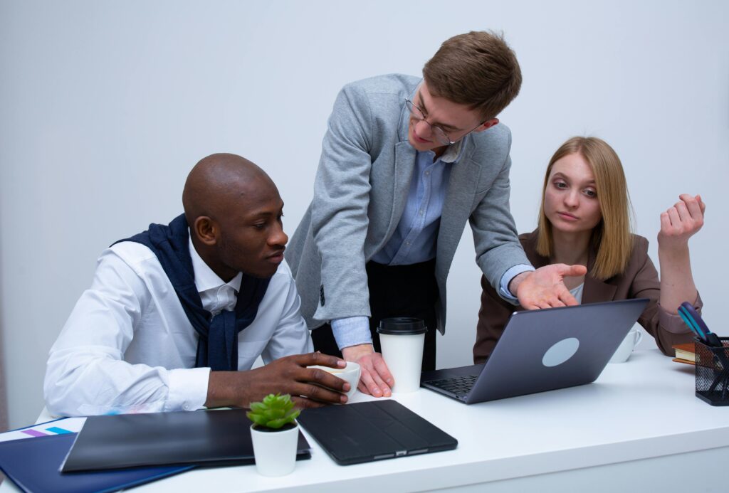 pexels-photo-6930542-6930542 Three professionals engage in a lively business discussion at a modern office desk, focusing on teamwork.